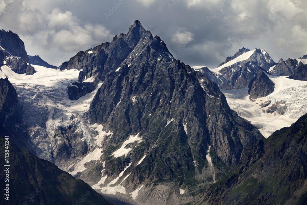 Mountains with glacier in clouds before rain