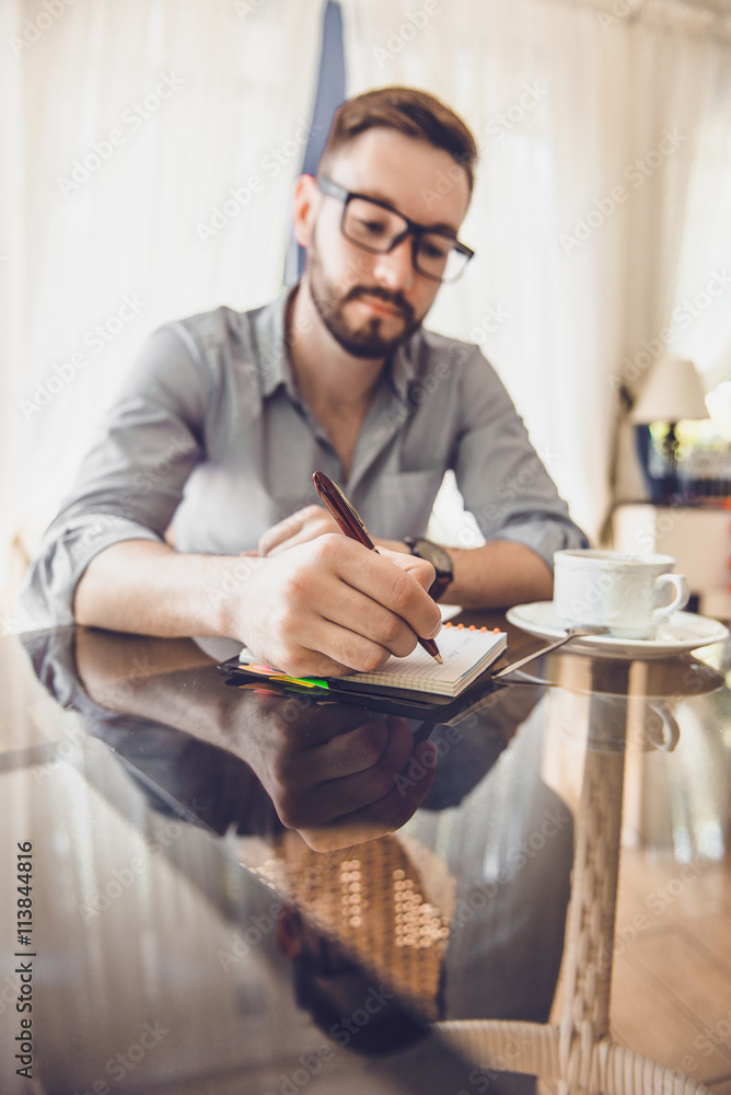 Fototapeta premium Businessman in a cafe drinking coffee and working on a Tablet PC