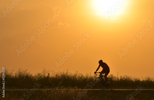 Cyclist riding bicycle on sunset sky, silhouette.
