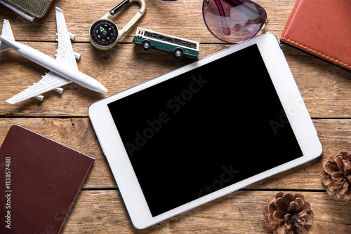 Travel gear and tablet on wooden background. Travel concept