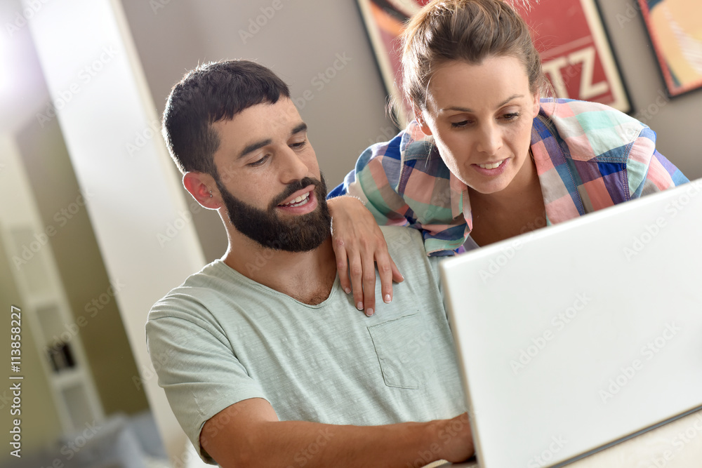 Couple at home looking at decoration website on laptop Couple at home looking at decoration website on laptop