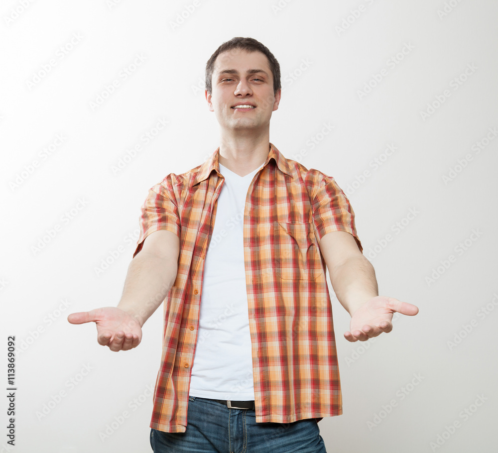 Smiling young man demonstrating inviting gesture Smiling young man demonstrating inviting gesture