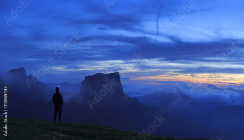 Hiker at his tent looking at a new dawn in the mountains. © sanderstock