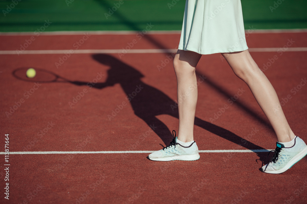 shadow of female tennis player in action on a tennis court (conc