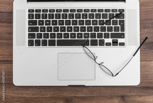 Laptop and glasses on wooden desk