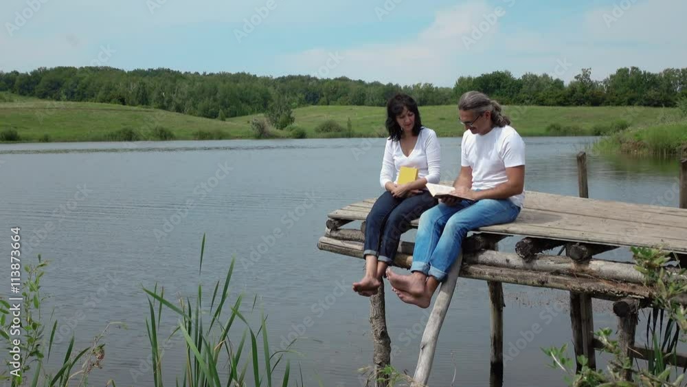 man and woman and discussing books on the board table near lake. 4K stock footage clip.
man and woman and discussing books on the board table near lake. 4K stock footage clip.