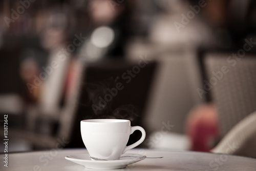 White cup of coffee at the summer cafe table