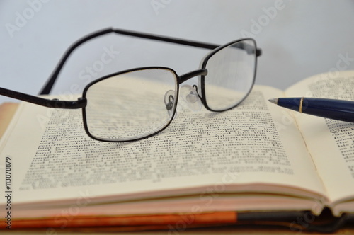 eyeglass and pen on book
