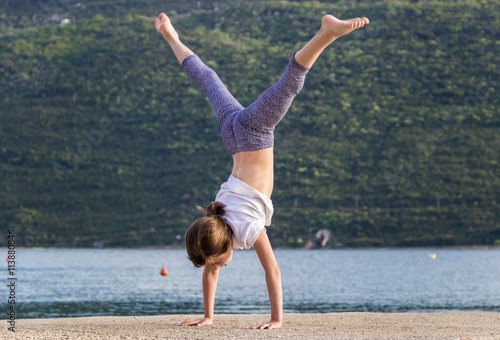 Юная девочка занимается акробатикой на пирсе в Черногории.