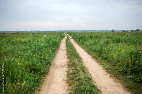 Road field in cloudly summer day