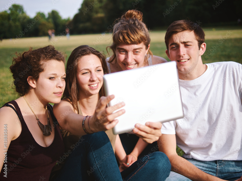 Obraz premium large group of friends tohether in a park using a tablet