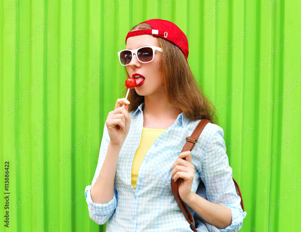 Fototapeta premium Portrait pretty cool girl with lollipop over green background