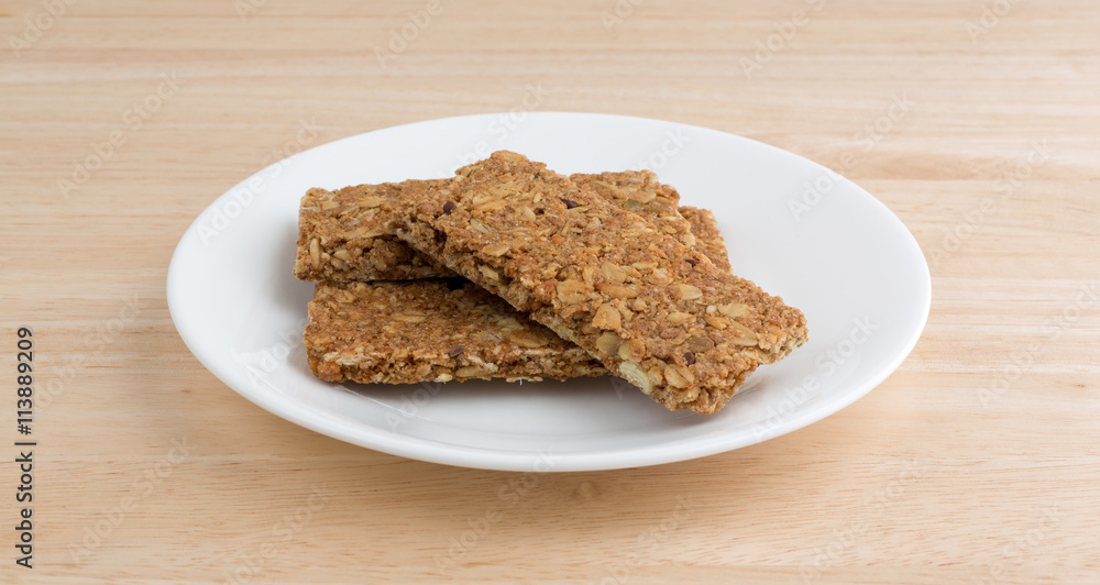 Cinnamon sesame and pumpkin seed granola bars on a plate atop a wood table top.