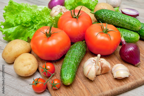 ripe tomatoes and other vegetables on a cutting board