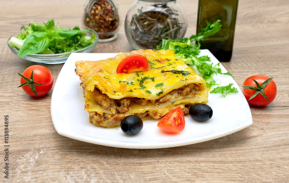 Appetizing lasagna with tomato and olives on a plate. Appetizing lasagna with tomato and olives on a plate.