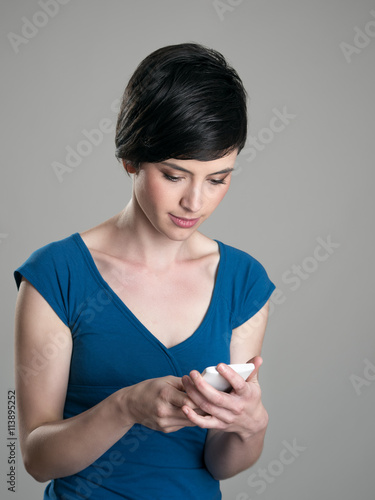 Young casual short hair beauty typing text message on smart phone with touch screen