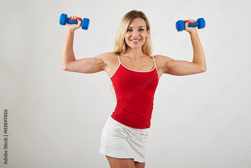 Attractive woman with athletic body holding dumbbells on white Attractive woman with athletic body holding dumbbells on white