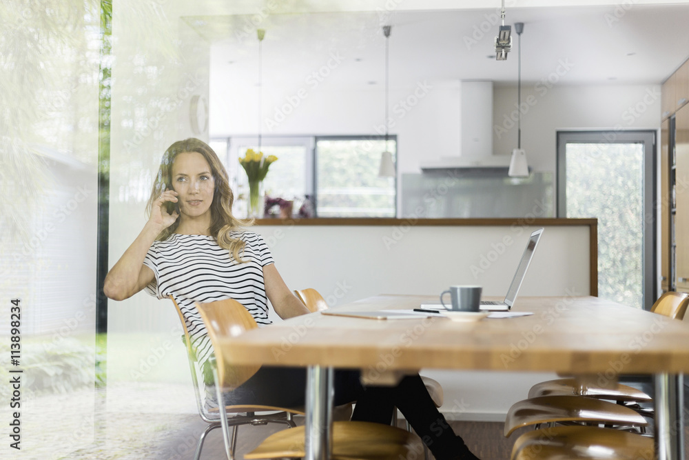 Woman on cell phone sitting at table Woman on cell phone sitting at table