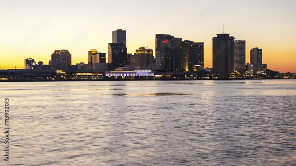 Downtown cityscape of New Orleans skyline across the Mississippi River, day to night timelapse (Building logos blurred for commercial use) Downtown cityscape of New Orleans skyline across the Mississippi River, day to night timelapse (Building logos blurred for commercial use)