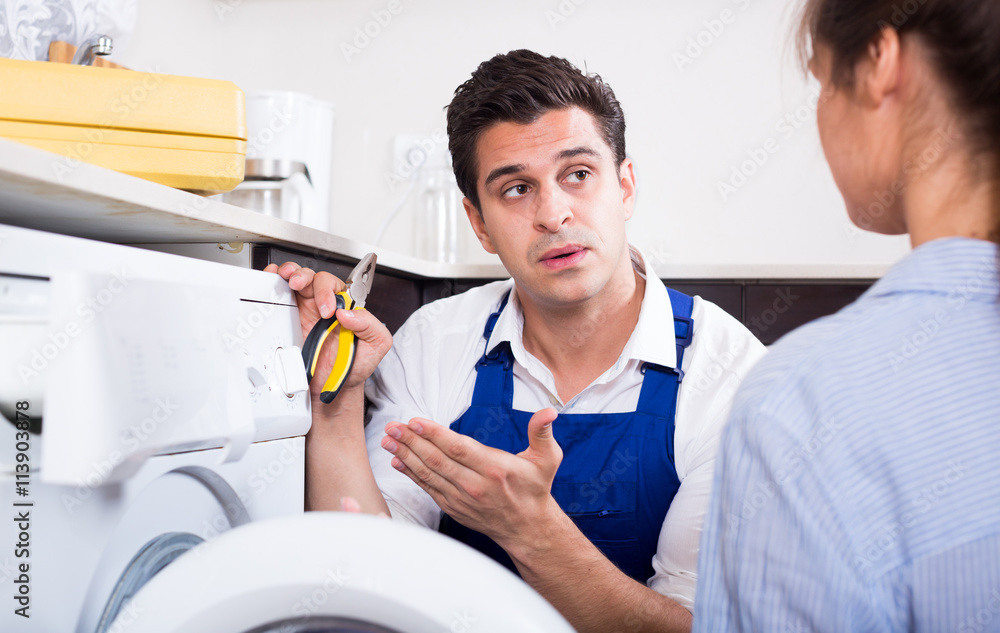 Obraz premium Repairman explaining woman how to use washer