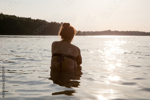 junge Frau von hinten in See sitzend
