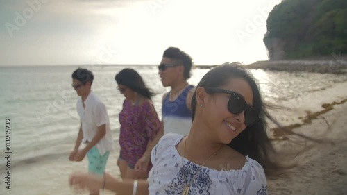 Attractive group of Japanese International friends walk along beach summer fun 