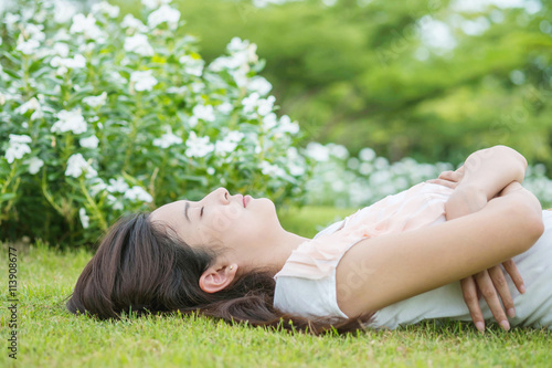 Asian woman lying and sleeping on grass field after she tired in the afternoon