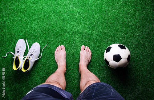 Barefoot football player against green grass, studio shot
