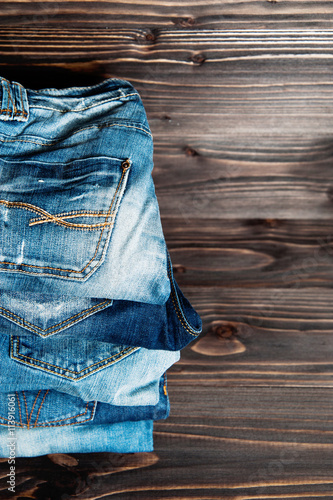 stack of various shades blue jeans on wood background