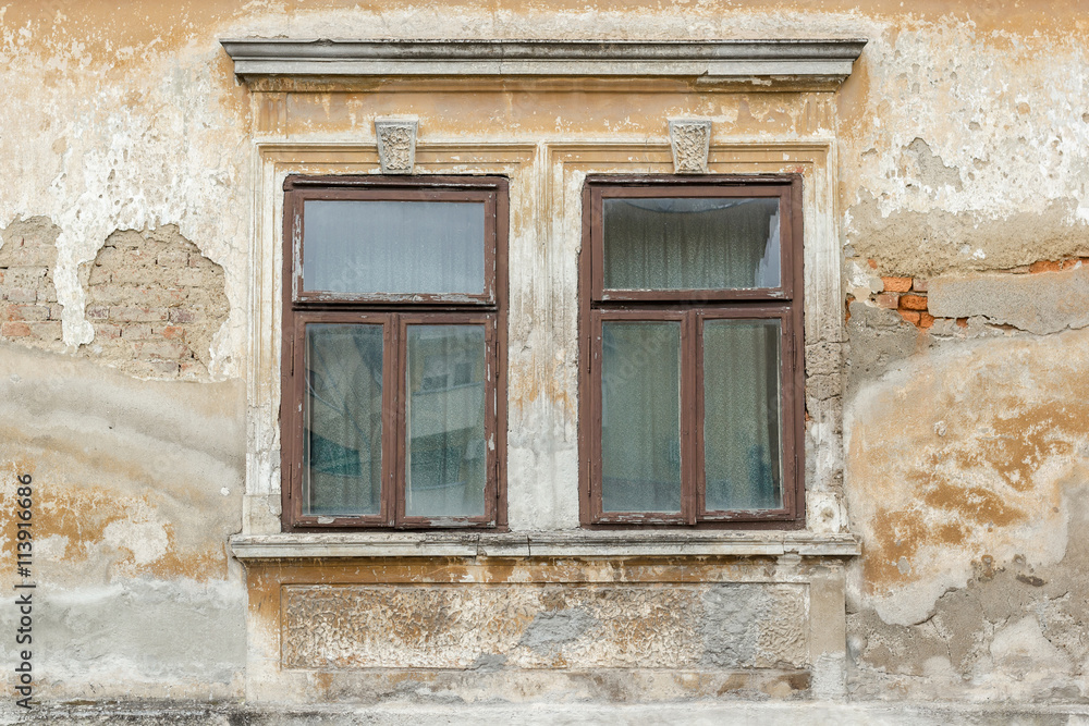 Two old broken windows on an abandoned old building