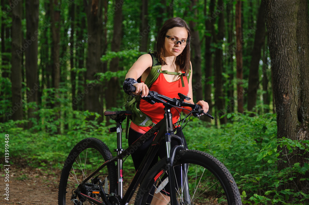Naklejka premium Girl riding a bike in the woods
