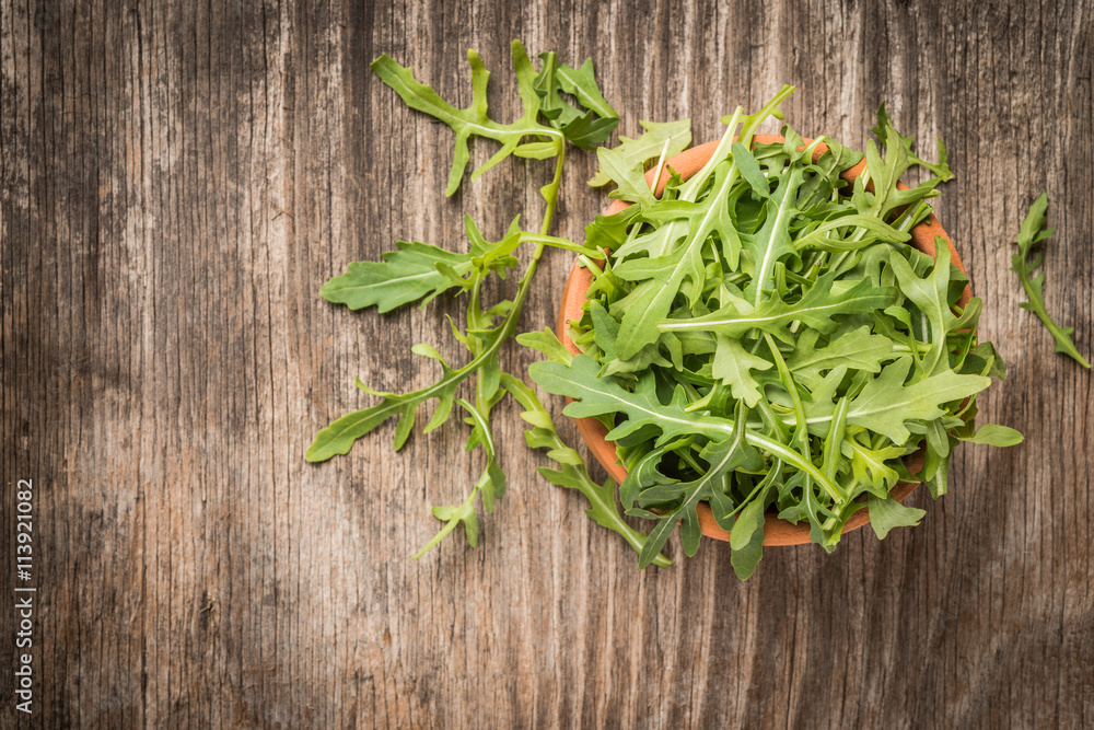 Fresh green arugula in bowl on wooden table Fresh green arugula in bowl on wooden table