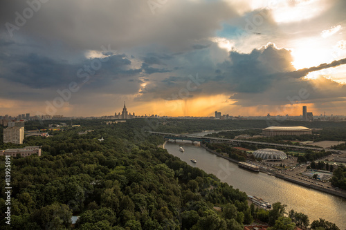 Rainy sunset clouds above river and a large city
