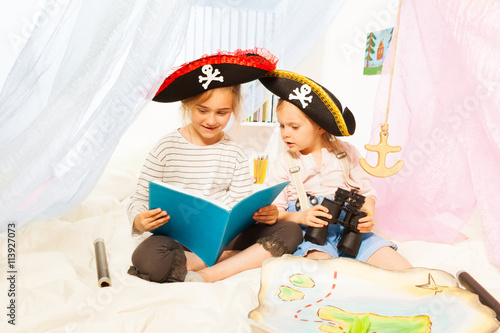 Two girls in pirate's costumes reading fairy-tale photo