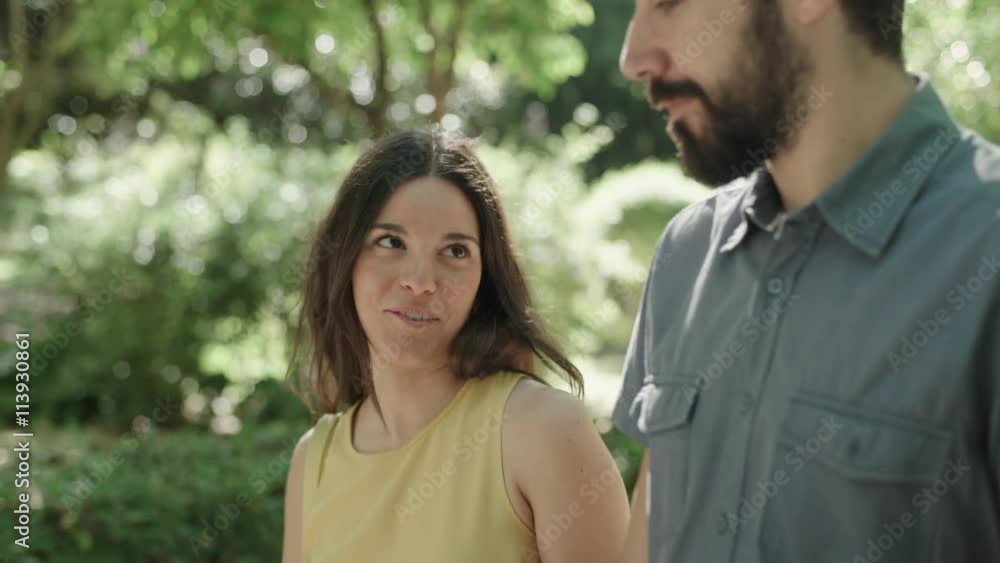 Young couple walking in the park. She talks and laughs. Dolly shot. Young couple walking in the park. She talks and laughs. Dolly shot.