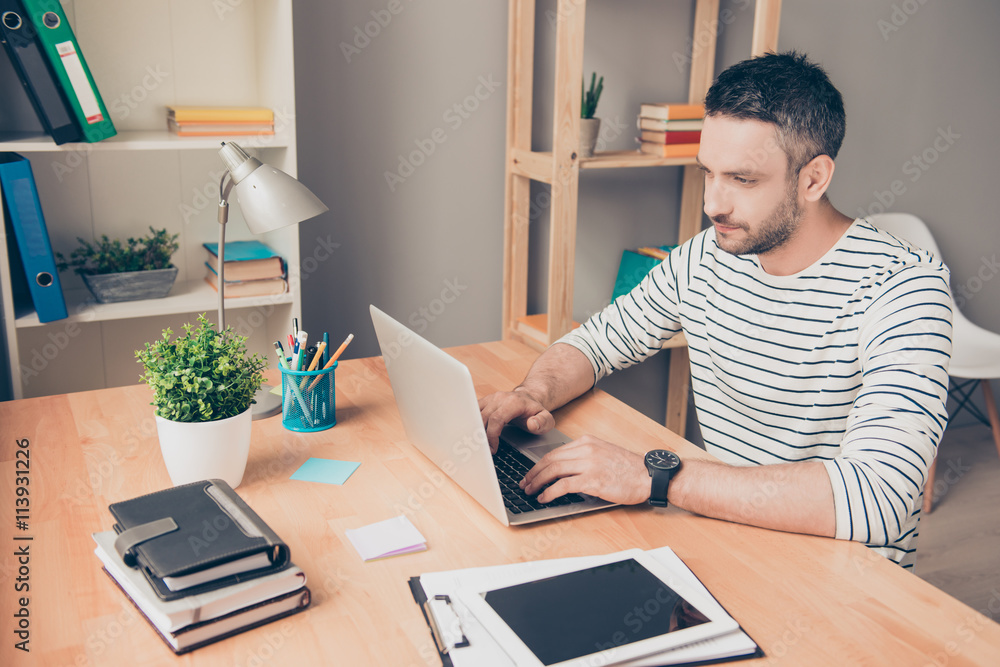 Smiling smart businessman in glasses working in office with lapt Smiling smart businessman in glasses working in office with lapt
