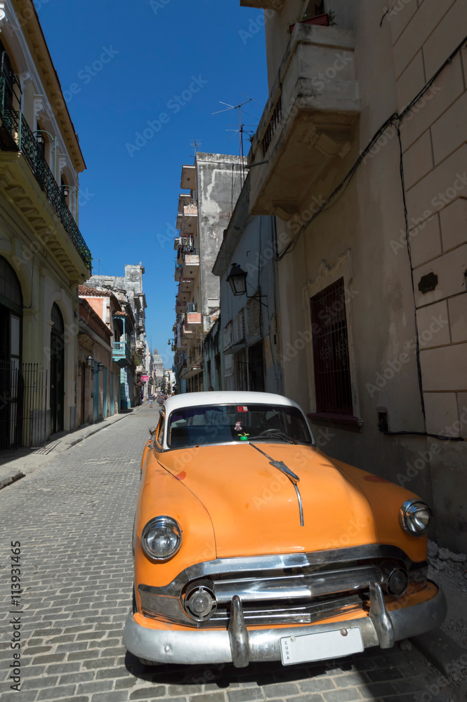 Orange american car parked in Old Havana under a blue sky