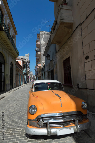 Orange american car parked in Old Havana under a blue sky © Roberto Lusso