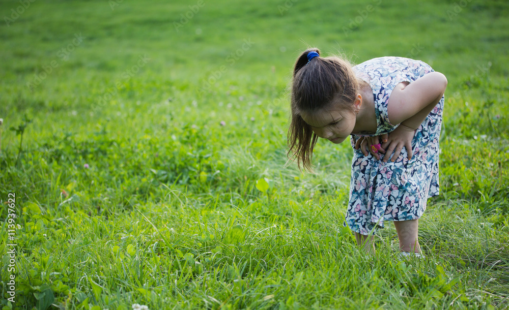 Fototapeta premium one little girl with magnifying glass outdoors in the day time