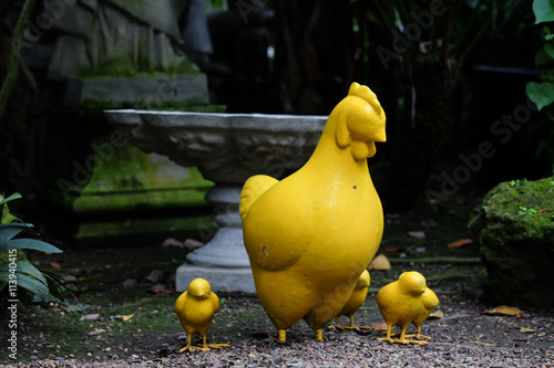 Yellow Chickhen family statues in the green garden photo