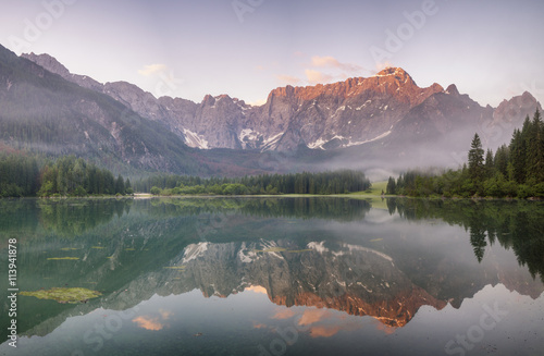 sunrise over a mountain lake, the peaks of the mountains lit by the rising sun