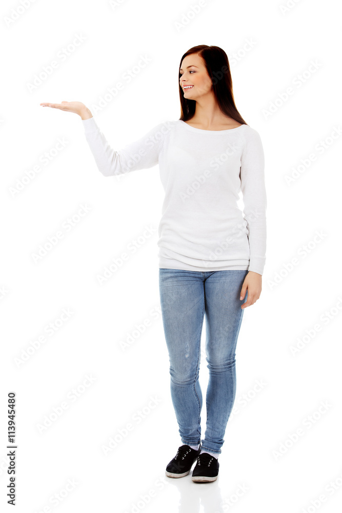 Smiling young woman presenting something on open palm Smiling young woman presenting something on open palm