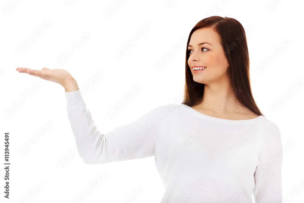 Smiling young woman presenting something on open palm Smiling young woman presenting something on open palm