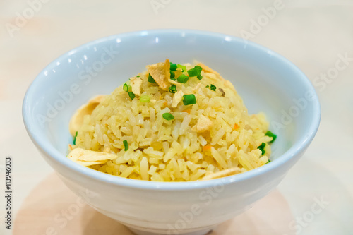 Thai garlic fried rice with vegetable on top in white bowl, on w