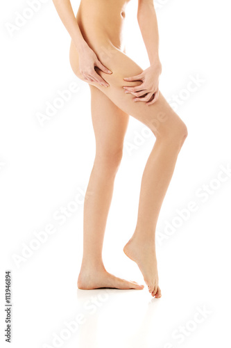 Female squeezes cellulite skin on her legs. Close-up shot on white background.