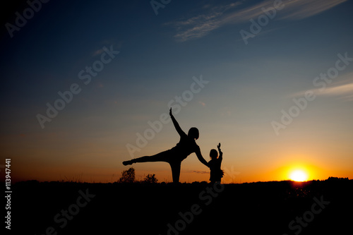 Silhouette, happy daugther with mother at sunset, summertime