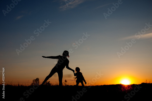 Silhouettes of mother and daughter at sunset. summertime