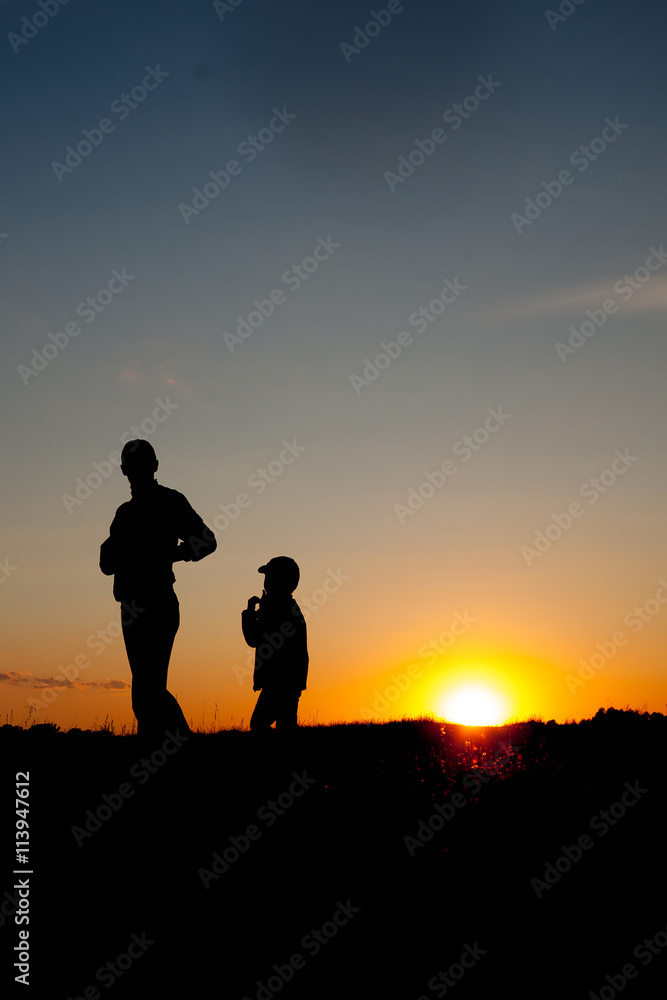 Silhouette of a man and his son with sunset background.  summertime