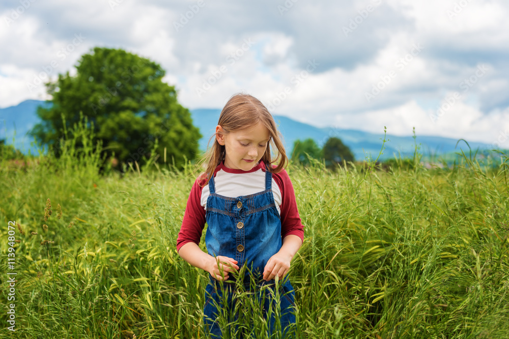 Little girl playing in green wheat field in summertime, wearing red and white t-shirt and overalls Little girl playing in green wheat field in summertime, wearing red and white t-shirt and overalls