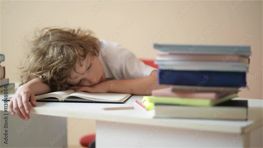 A child of primary school age do homework. The boy does his homework at his desk at home.pupil has been bored on the lesson A child of primary school age do homework. The boy does his homework at his desk at home.pupil has been bored on the lesson